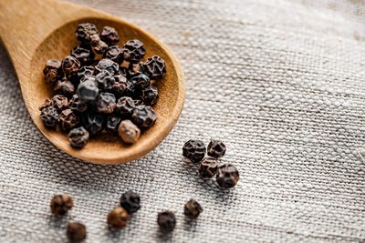 Black peppercorns on a wooden spoon